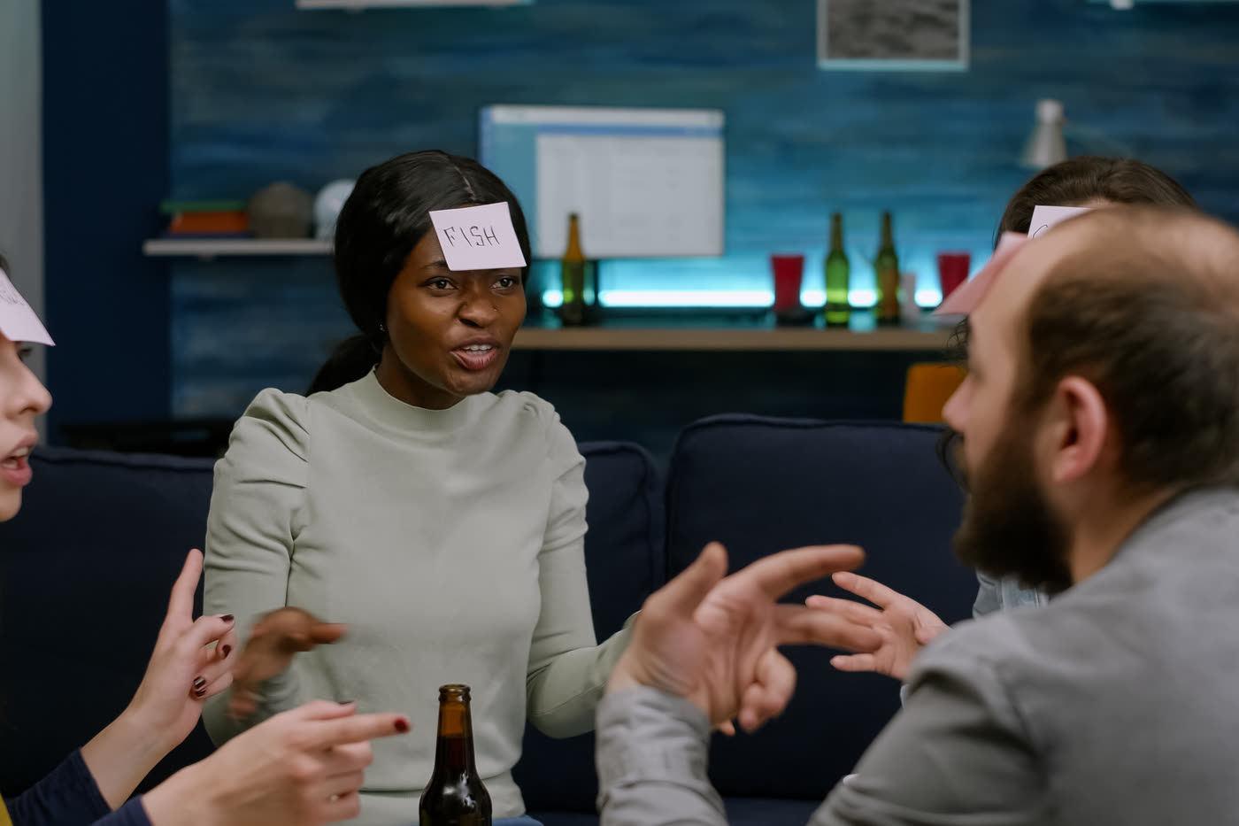 Friends in a living room laughing while guessing at each other’s answers