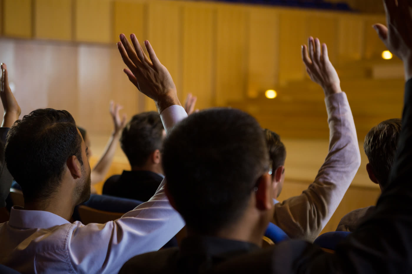 A room of people with their hands up, laughing, during a live game