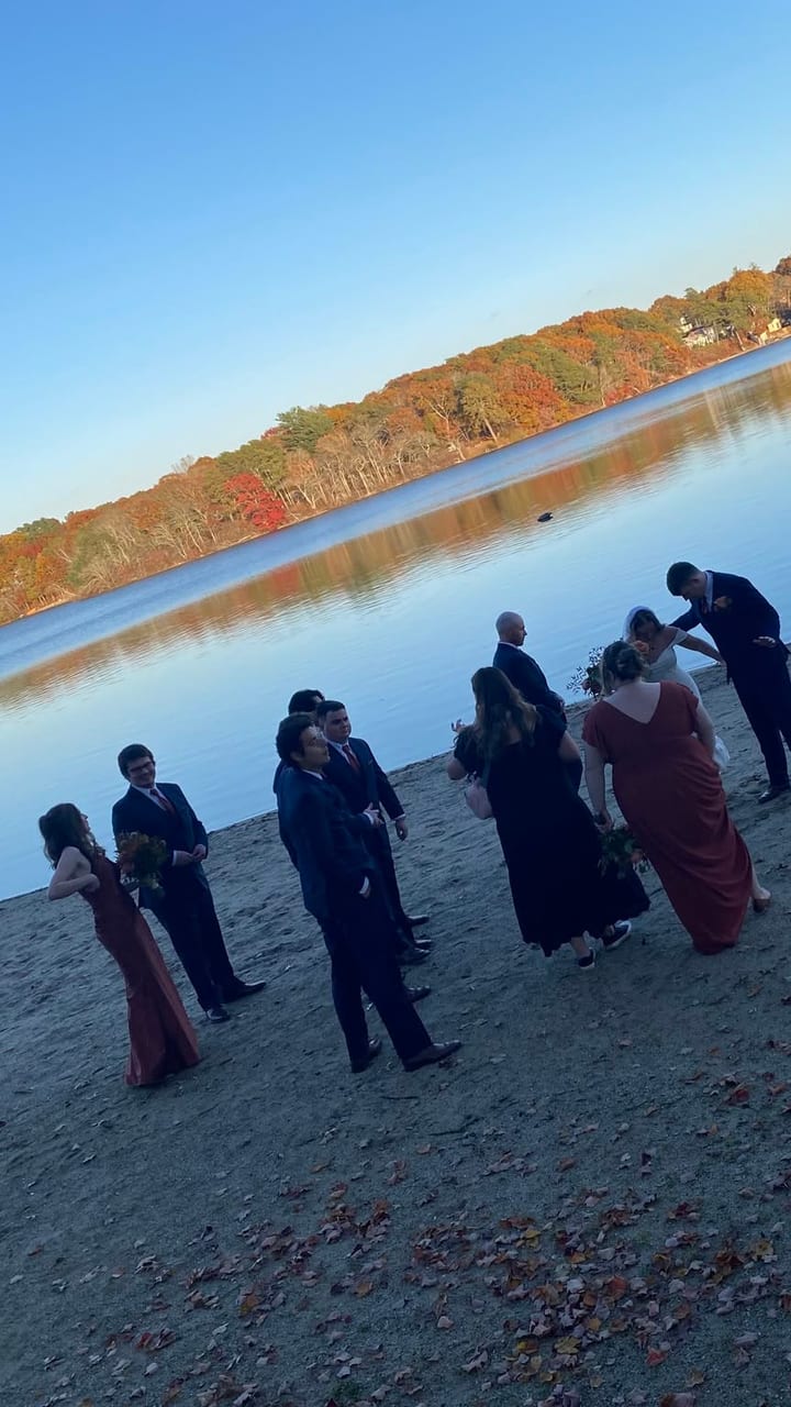 A wedding party gathered on the beach at dusk