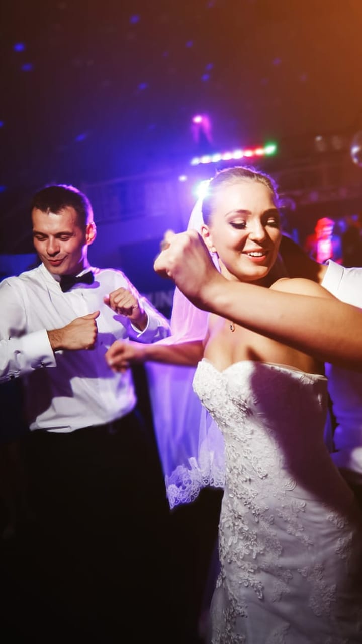 A couple dancing under colored party lights